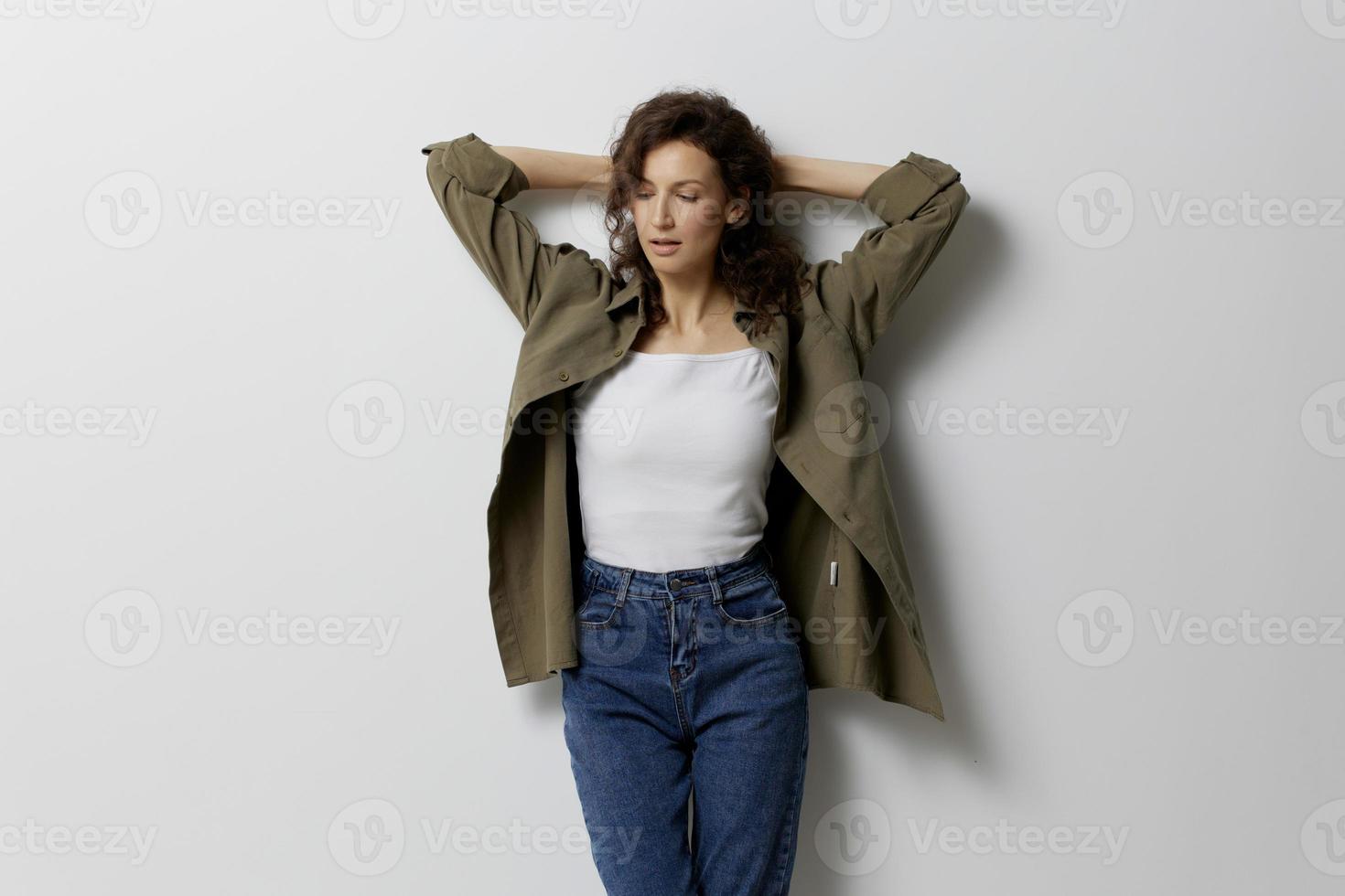 Pensive curly beautiful woman in casual khaki green shirt think about work problems cross hands behind head posing isolated on over white background. People Emotions Lifestyle concept. Copy space photo