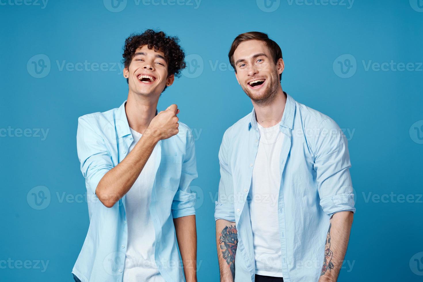 Happy friends in identical shirts chatting on a blue background fun model photo