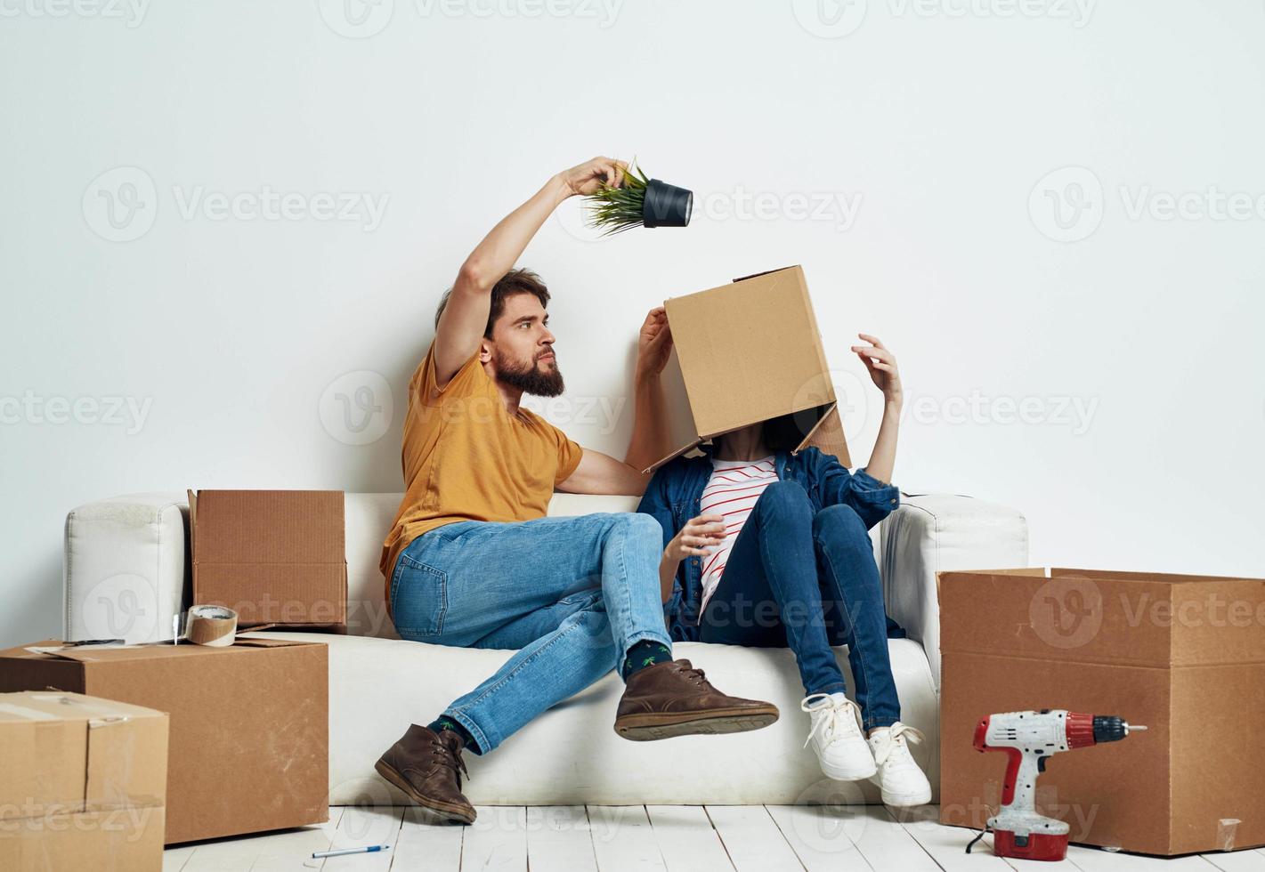 man and woman on couch moving boxes with things interior photo