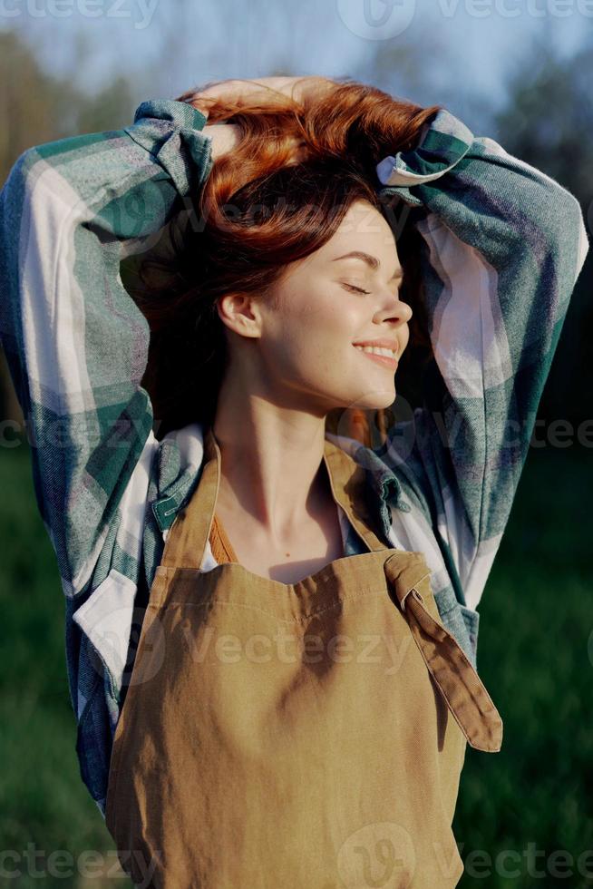 Portrait of a woman with a beautiful smile in her work clothes and apron in nature, enjoying relaxation after work in the sunset sunlight photo