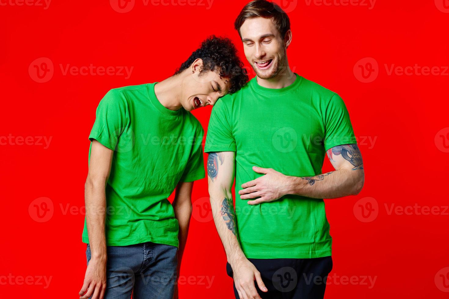 Two cheerful friends in green t-shirts are standing next to each other emotions isolated background photo