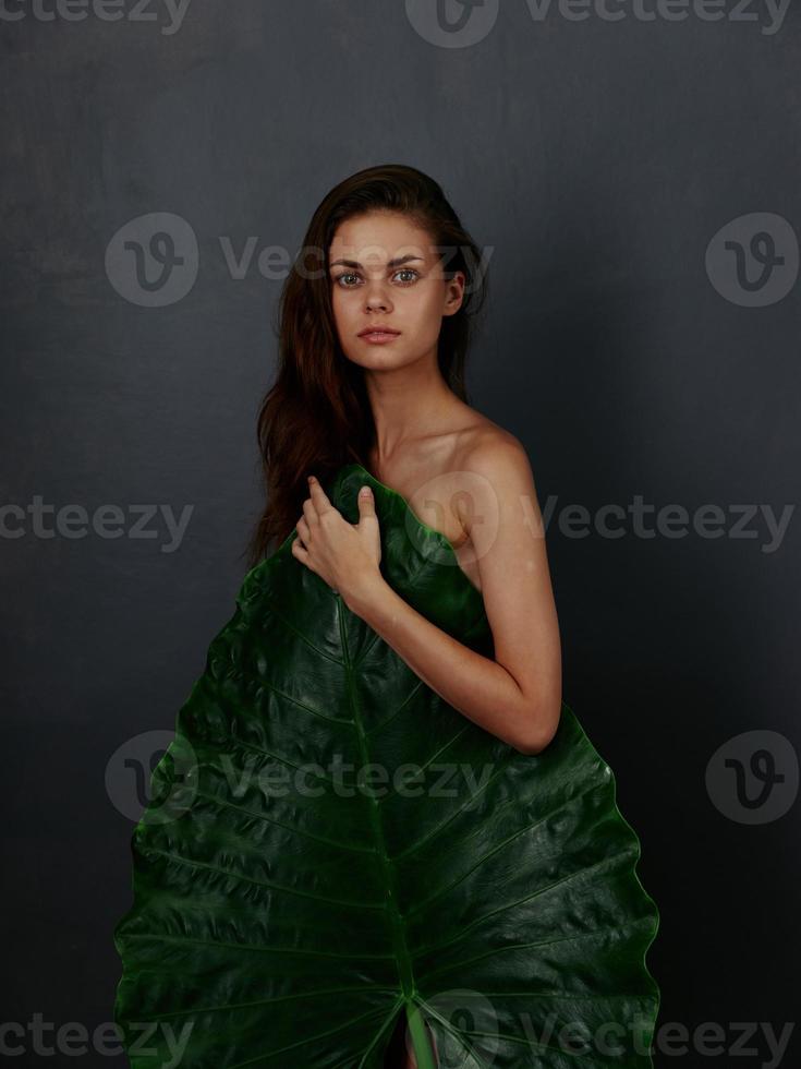 red-haired woman with naked body palm leaf dark background photo