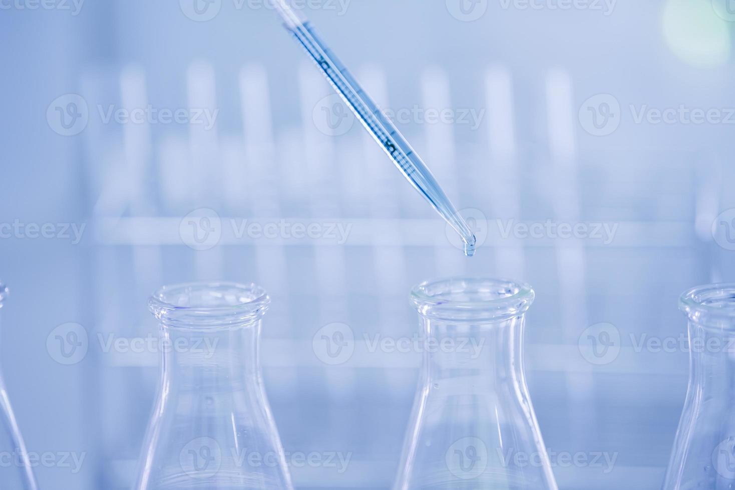 Doctor or scientist using pipette to drop a sample to test tube in medical research lab or science laboratory photo