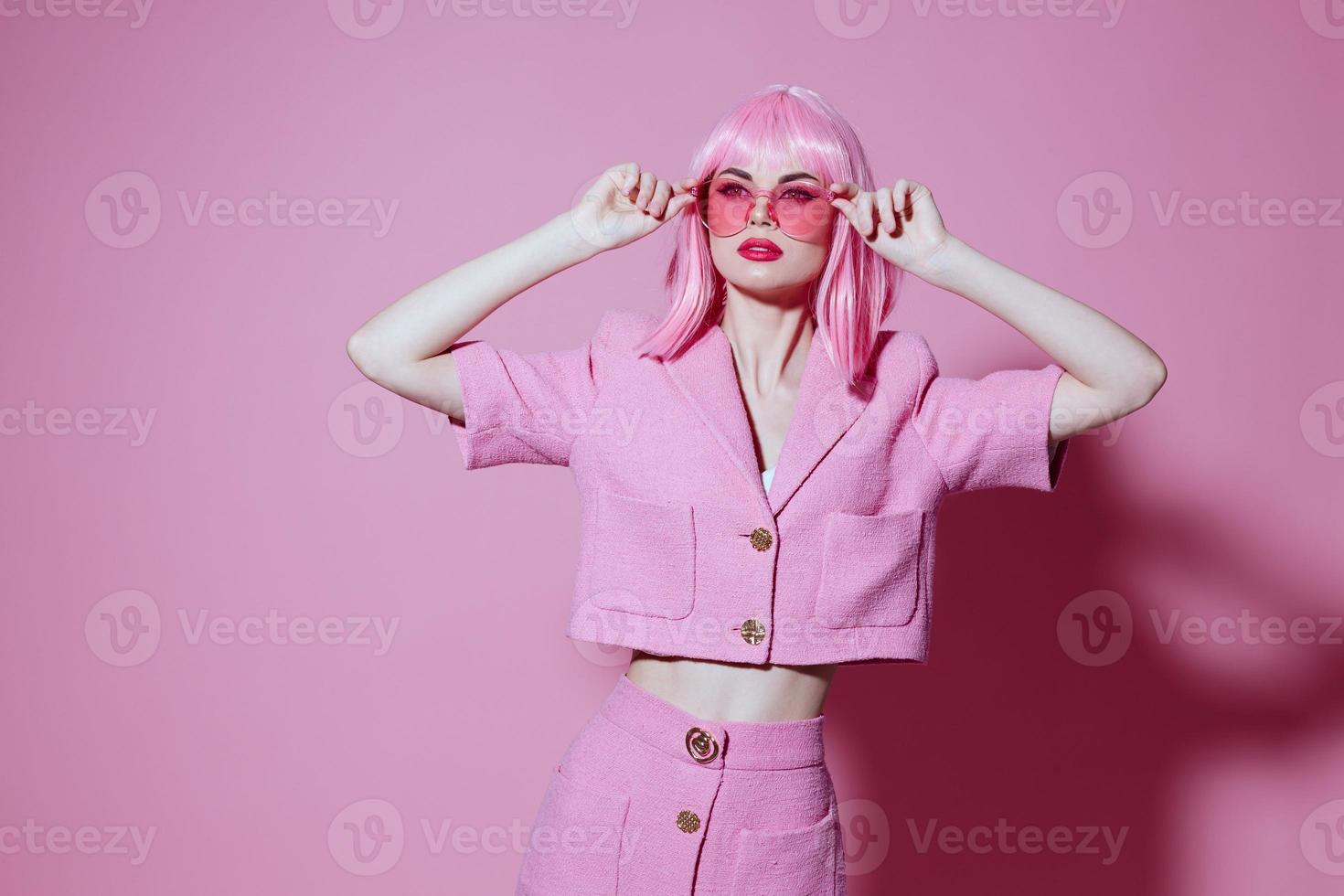 Pretty young female gestures with his hands with a pink jacket pink background unaltered photo