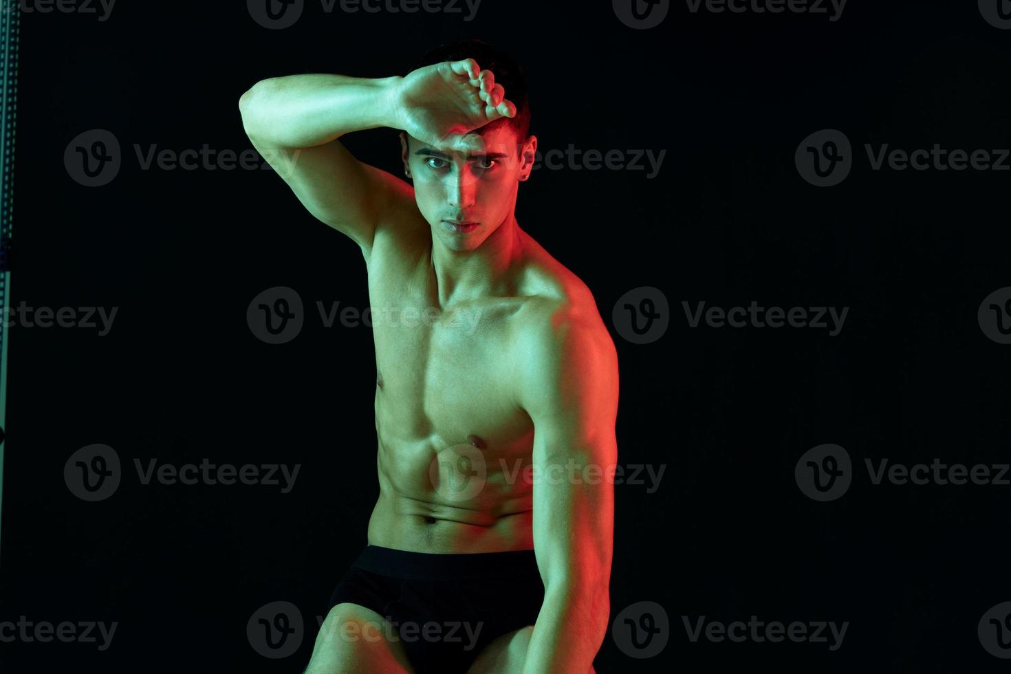 sporty man with pumped muscles on his stomach posing on isolated background cropped view photo