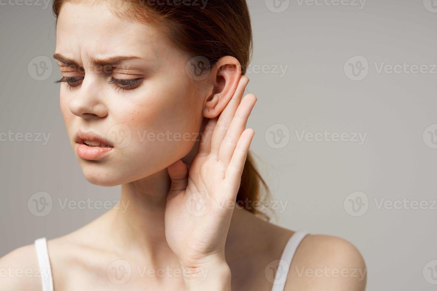 sick woman poor hearing disorders in white t-shirts light background photo