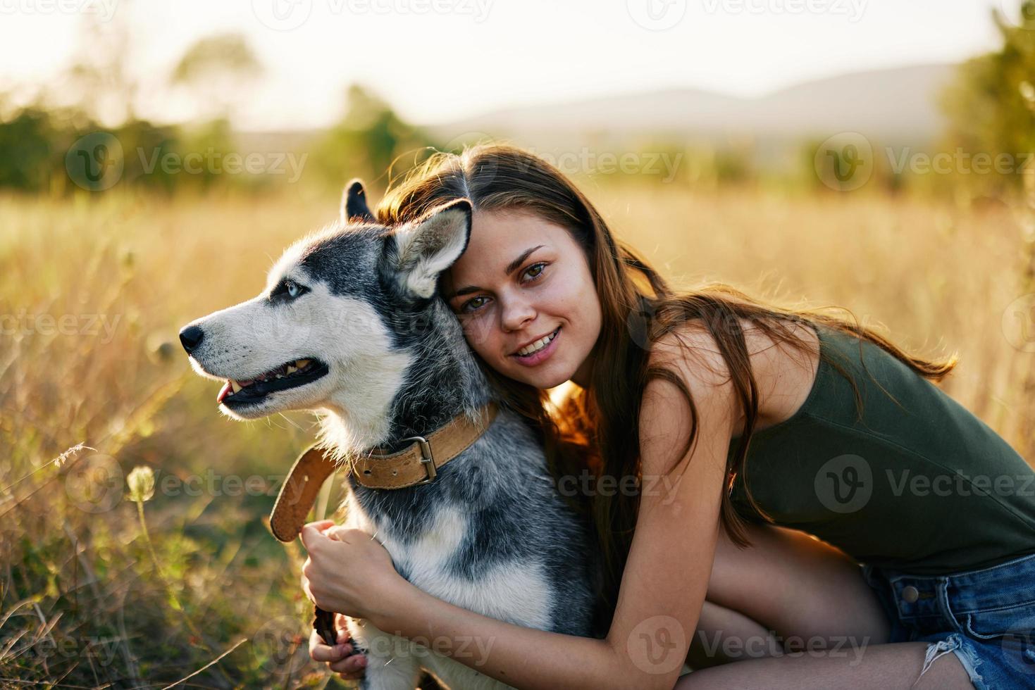 mujer sonriente y abrazando su perro sentado en un campo con un perro tejonero perro sonriente mientras gasto hora al aire libre con un amigo perro en otoño a puesta de sol mientras de viaje foto