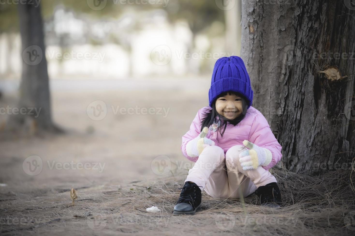 Portrait of cute asian little girl wear Winter clothes at the forest of the park,Thailand people pose for take a picture,Happy time photo