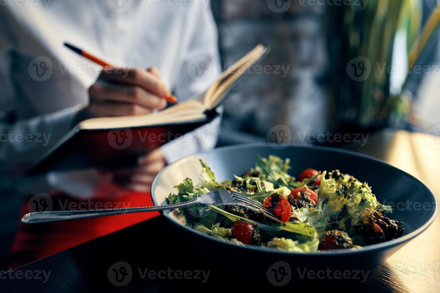 notepad with a pen in hand and salad in a plate restaurant cafe inscription photo
