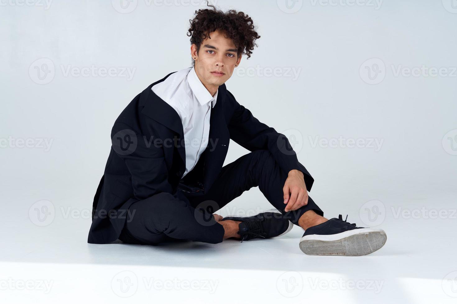 guy sitting on the floor curly hair suit modern style isolated background photo