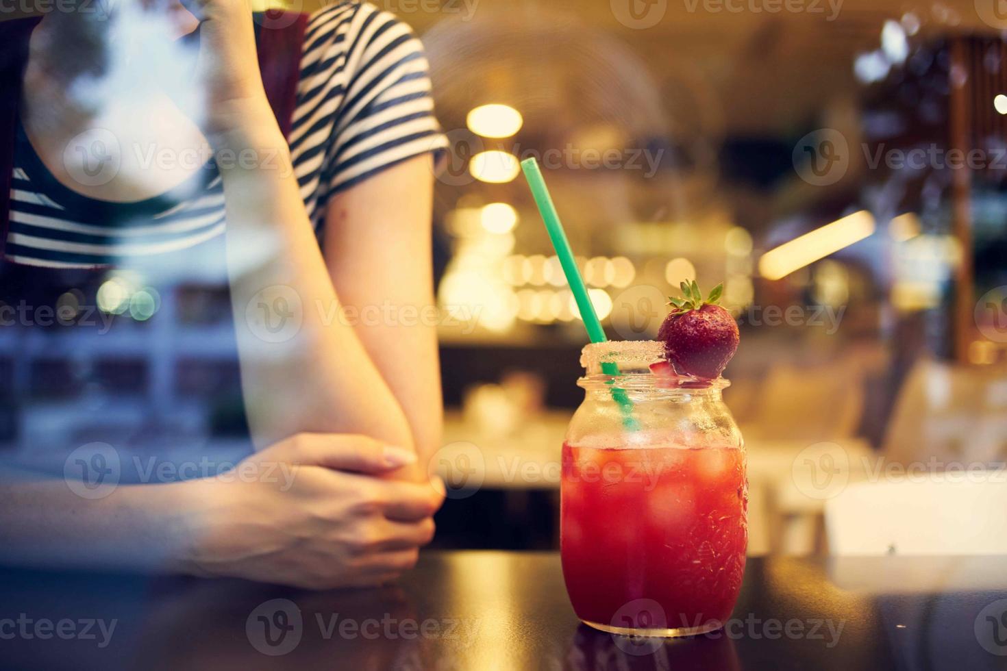 a woman in glasses with a short hairstyle sits alone in a restaurant cocktail photo