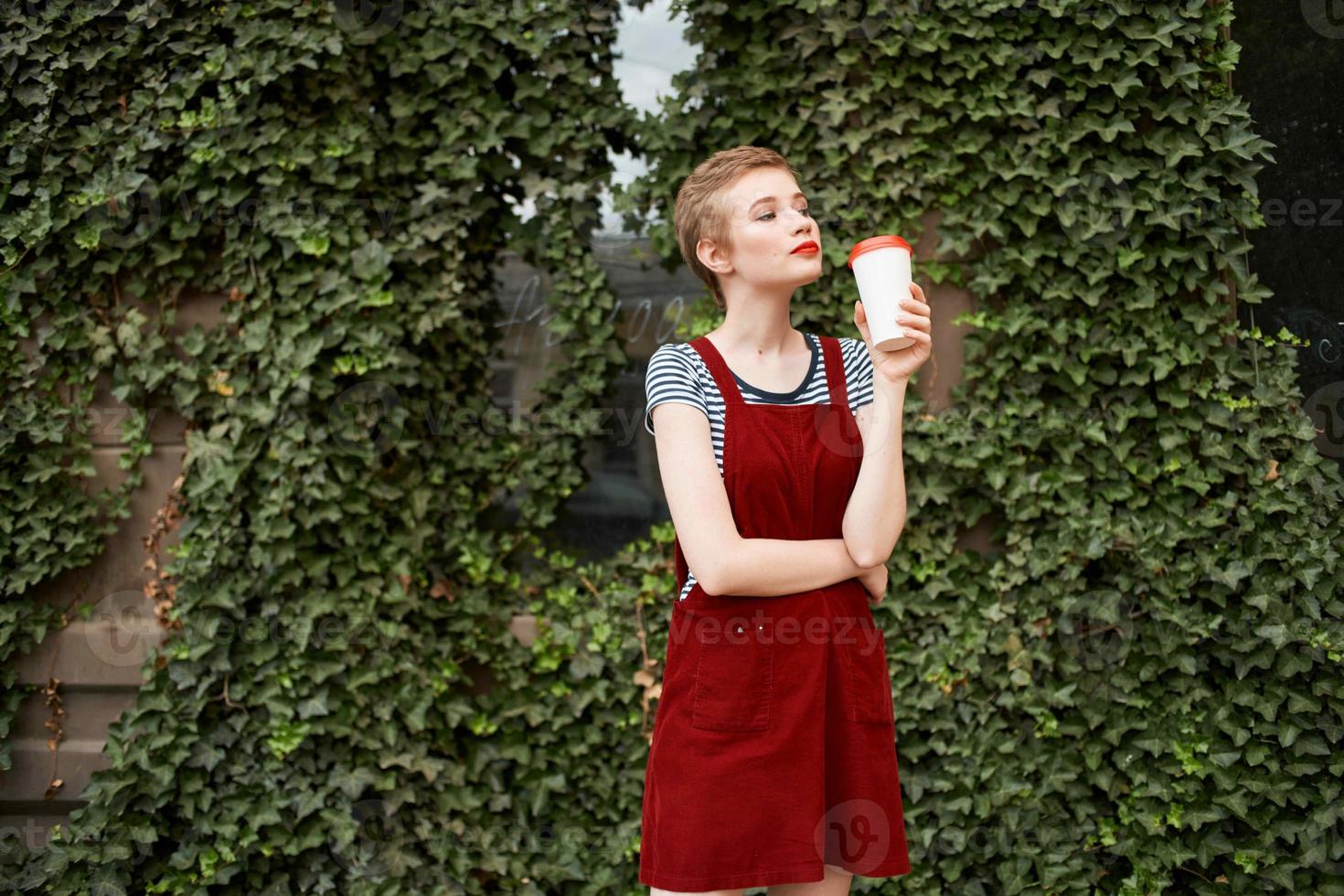woman holding a cup of coffee in her hands on the street near the bushes summer vacation photo