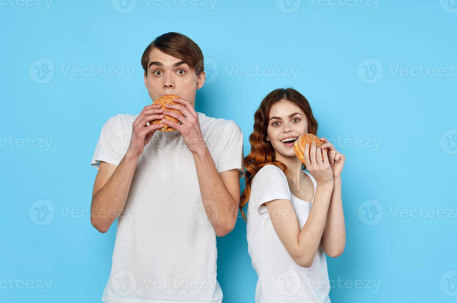 young couple hamburgers in hands snack lifestyle blue background photo