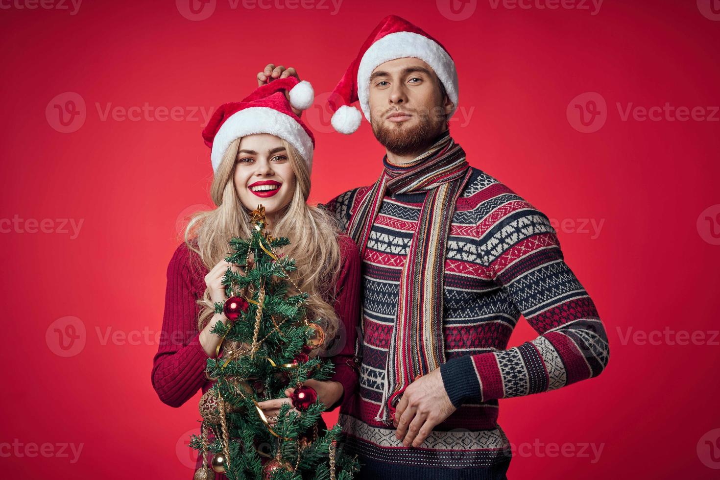 a man and a woman are standing next to the new year tree decoration holiday photo