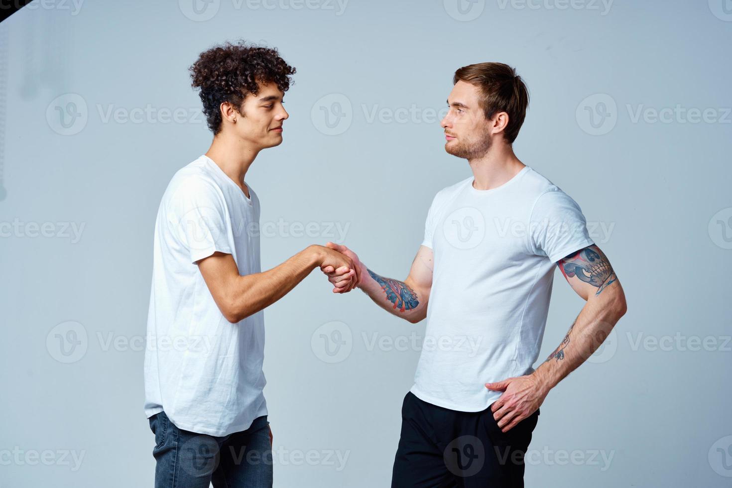 Two cheerful friends in white t-shirts emotions studio photo