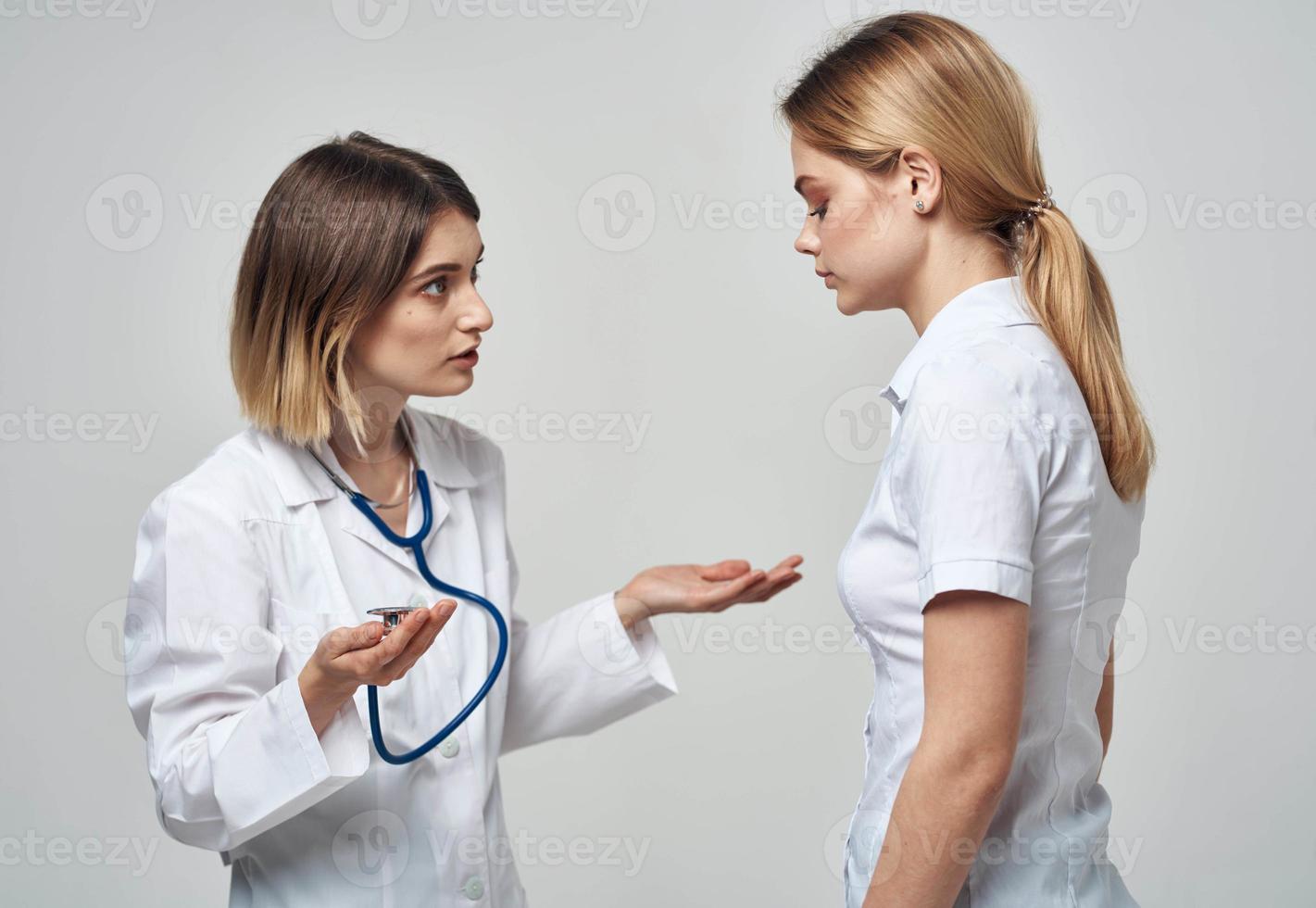 A nurse with a stethoscope and a patient on a light background photo