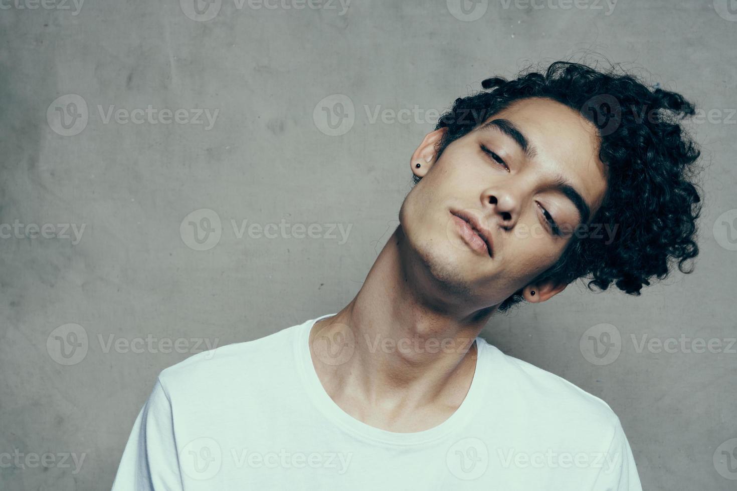 retrato de un atractivo joven hombre en un camiseta con Rizado pelo de cerca tela antecedentes foto