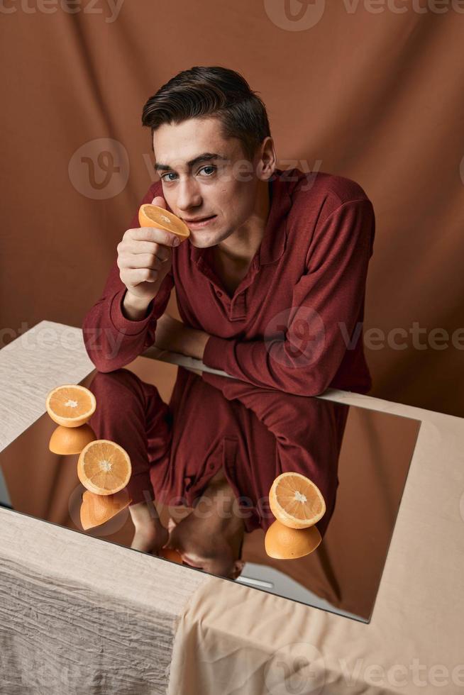 Man with oranges on the mirror at the table top view fabric background photo