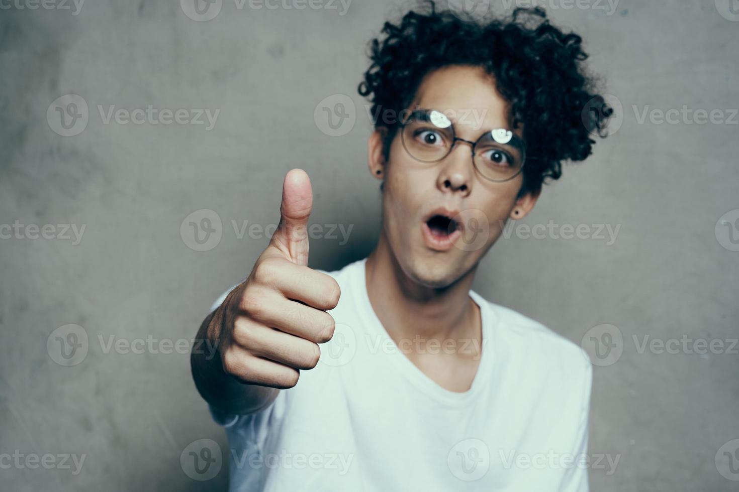 curly-haired guy sitting on a chair with glasses fashion studio photo