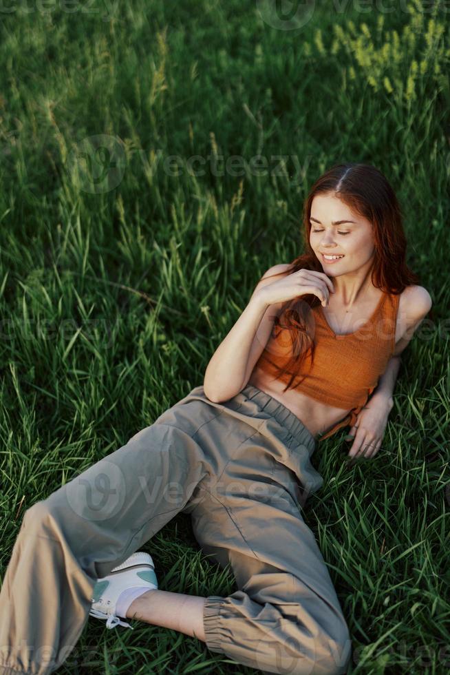 A young happy woman lying relaxed on the grass in the park, the lifestyle of a happy person without depression photo