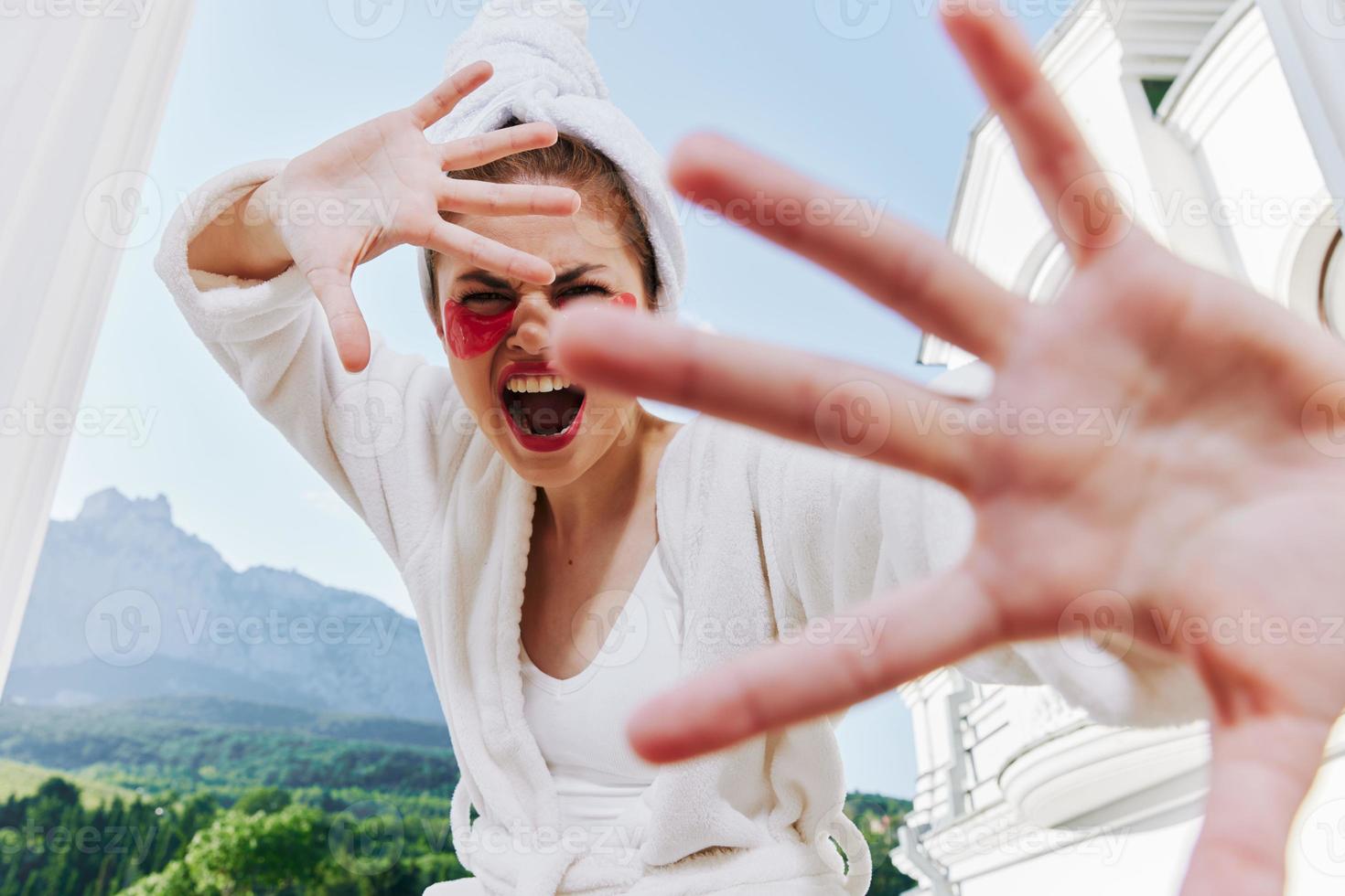 emotional woman in a white coat holds her hand in front of her photo