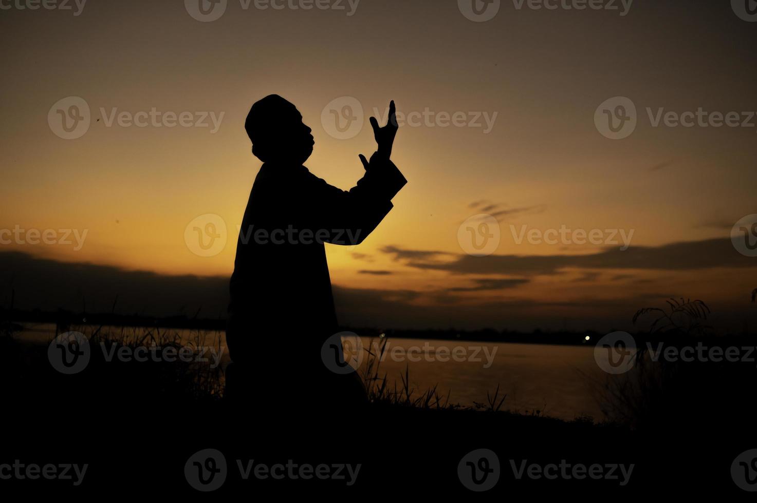 Silhouette Young asian muslim man praying on sunset,Ramadan festival concept photo