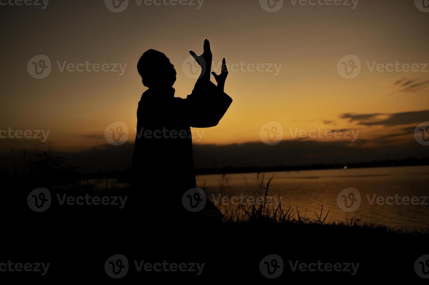 Silhouette Young asian muslim man praying on sunset,Ramadan festival concept photo