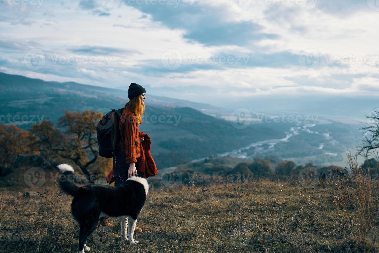 mujer con mochila en naturaleza siguiente a perro caminar montaña paisaje foto