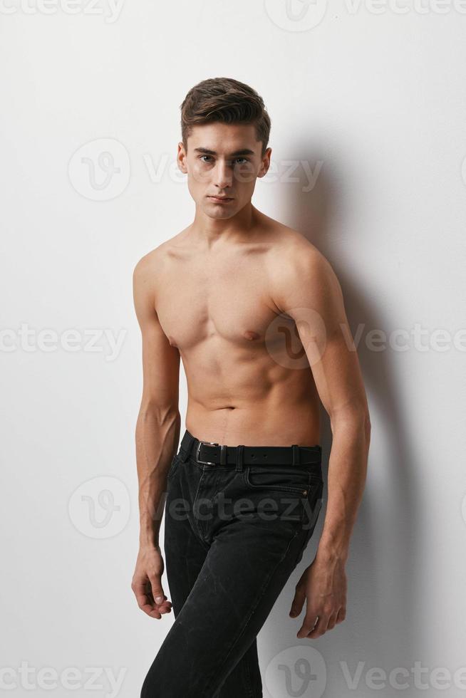 A man with a naked torso and in trousers on a light background cropped view photo
