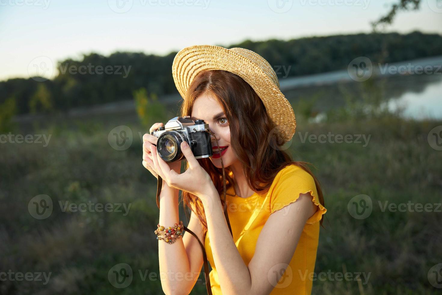 woman photographer looking into the camera lens wearing a hat outdoors takes a picture photo