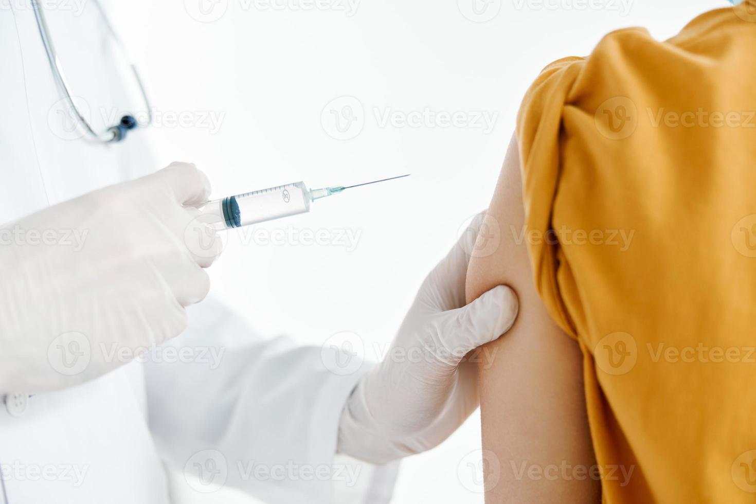 doctor giving injection to patient's shoulder close-up cropped view syringe epidemic covid photo