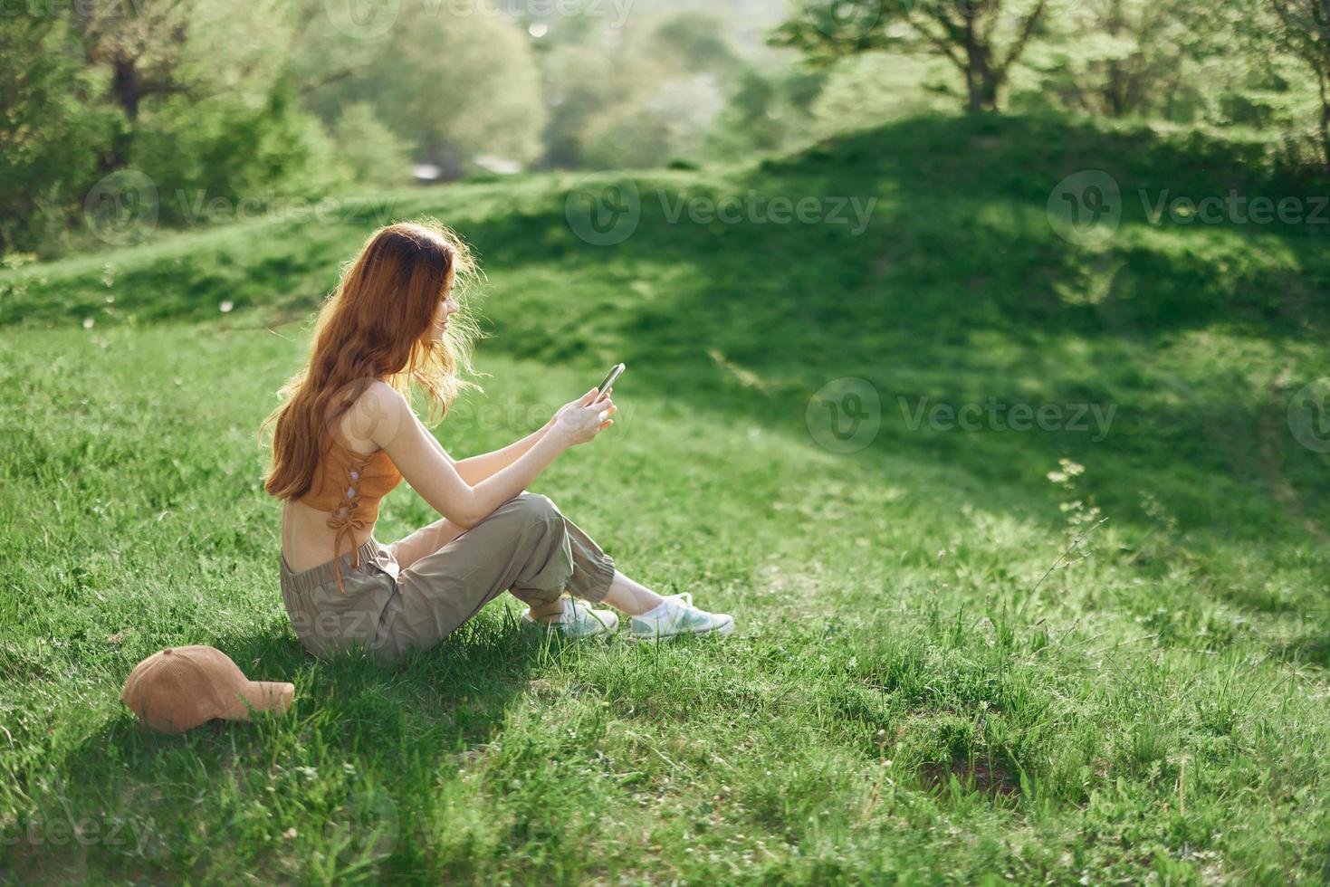 Top view of a woman with phone in hand freelance student trying to find internet connection in nature in a green summer park photo