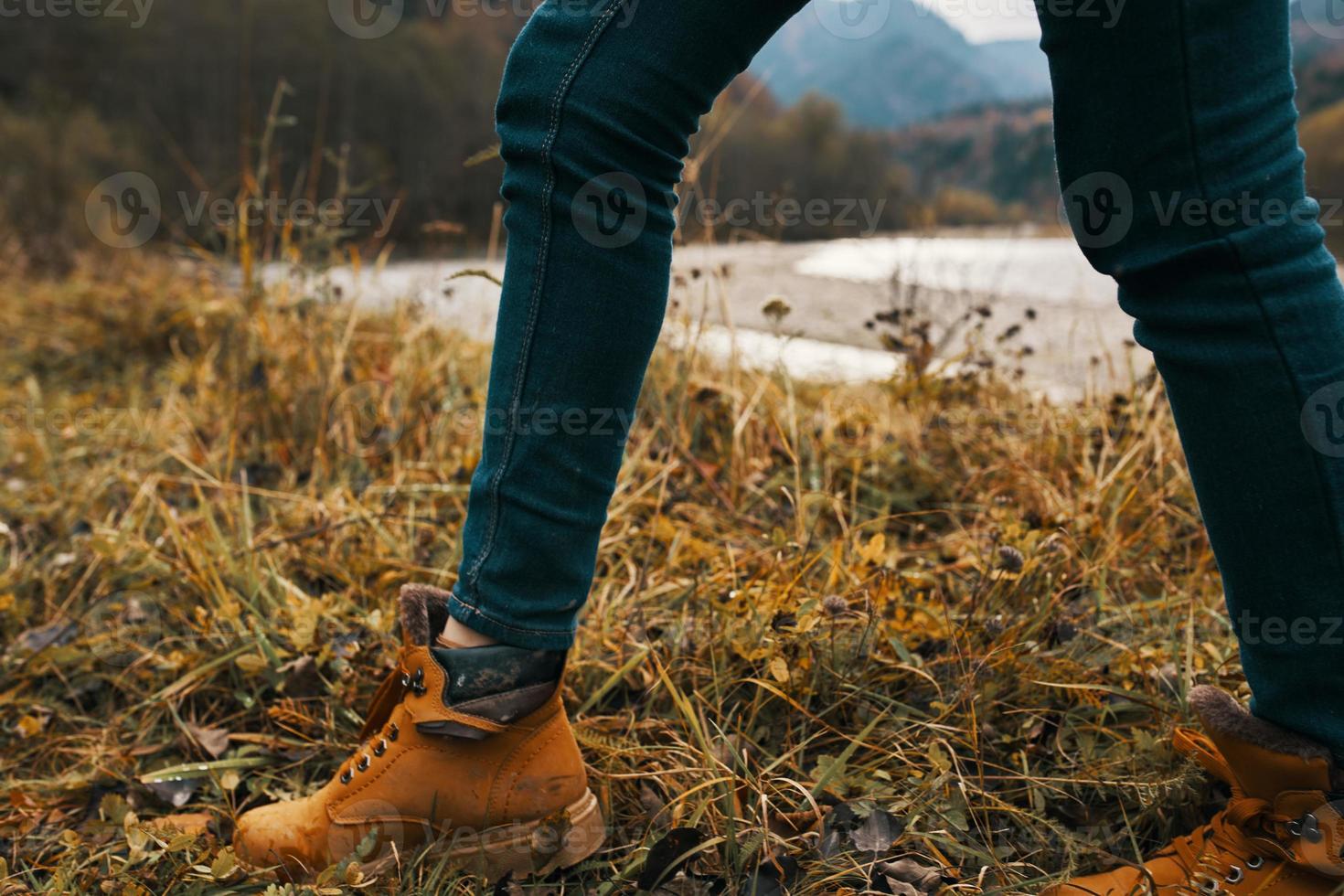 female legs in boots and jeans on nature in autumn in the mountains photo