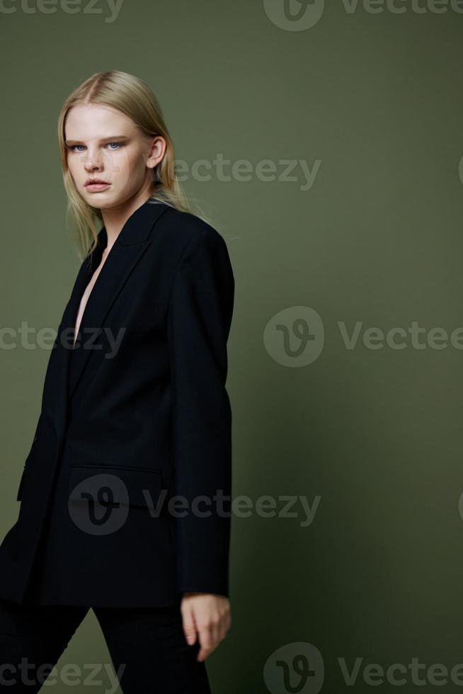 A bright expressive strict girl professional model walks to the side in motion looks at you in the camera posing on a green olive background in the studio photo