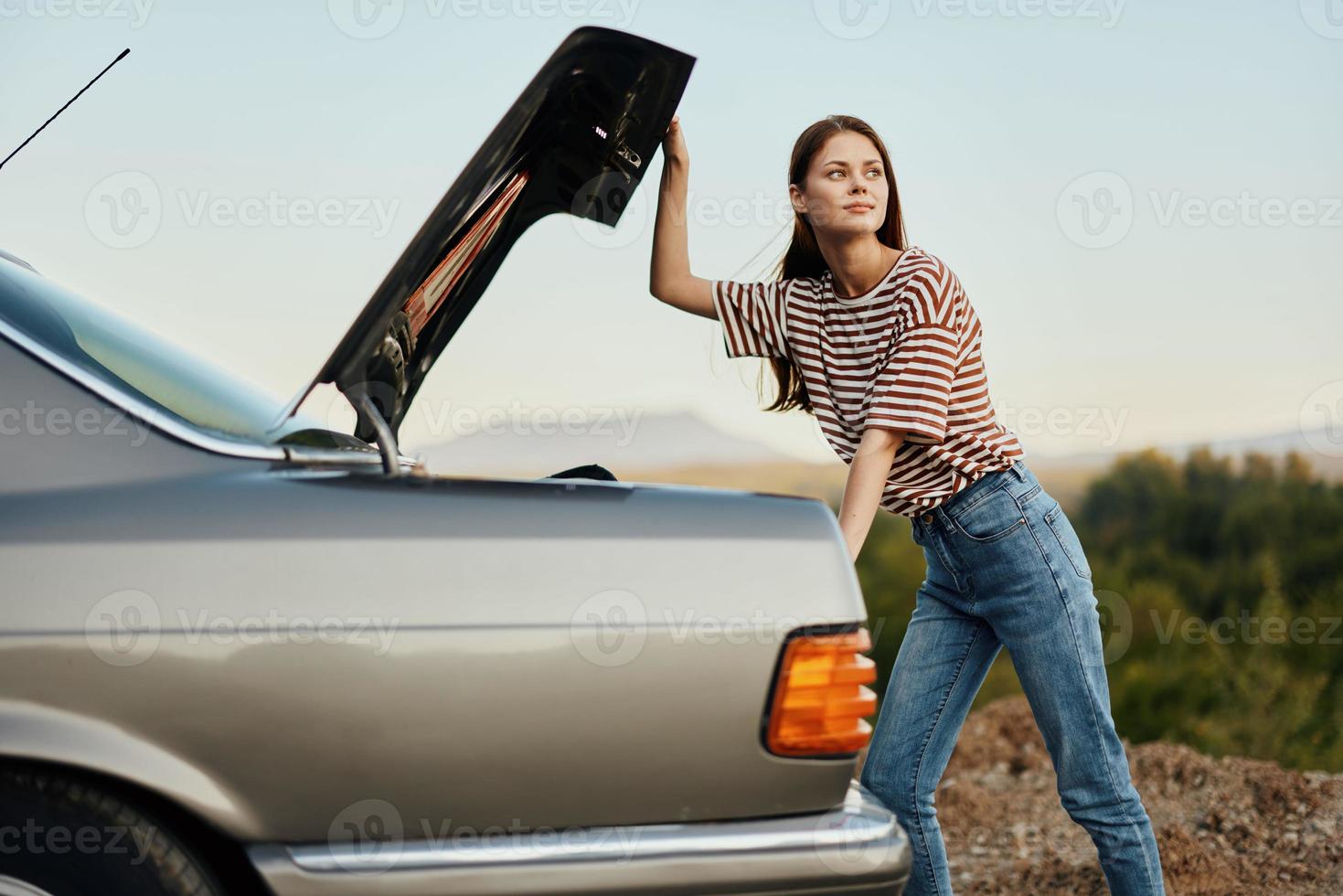 el mujer conductor de el coche abrió el maletero con aspecto. coche Descompostura mientras de viaje en el la carretera. coche y mujer reparar concepto foto