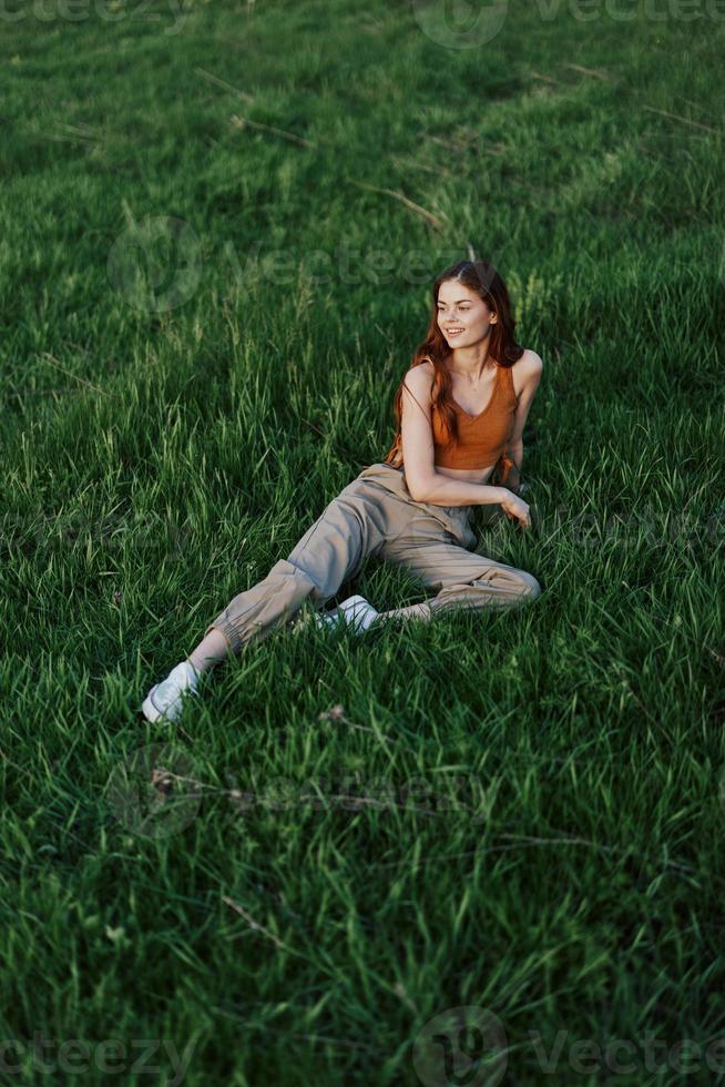 A woman lies on fresh spring green grass in a park without mosquitoes or ticks and enjoys relaxing while watching the sunset. The concept of safe outdoor recreation photo
