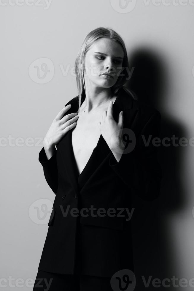 A stylish woman holds a jacket collar while posing in the studio. Fashionable stylish photo. Concept for clothing brands photo