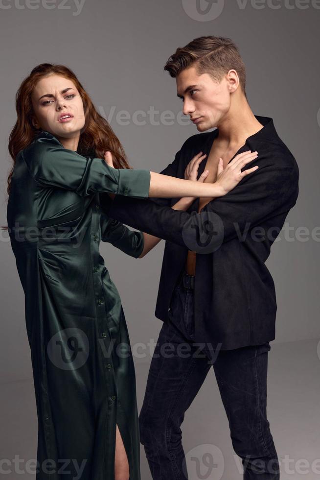 Domestic violence aggressive man holding a woman by the hair on a gray background photo