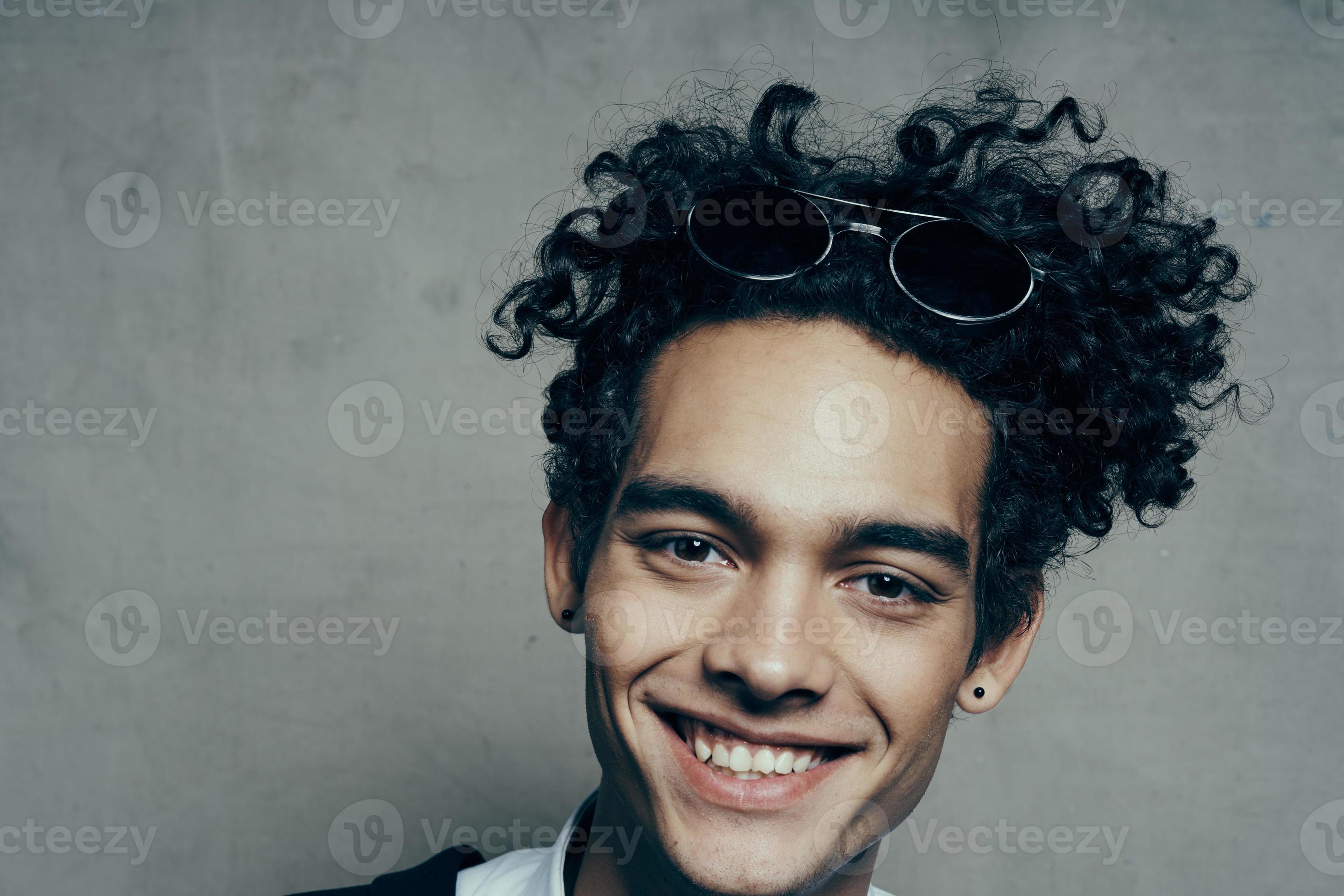 handsome guy with curly hair in a white shirt and jacket on a gray