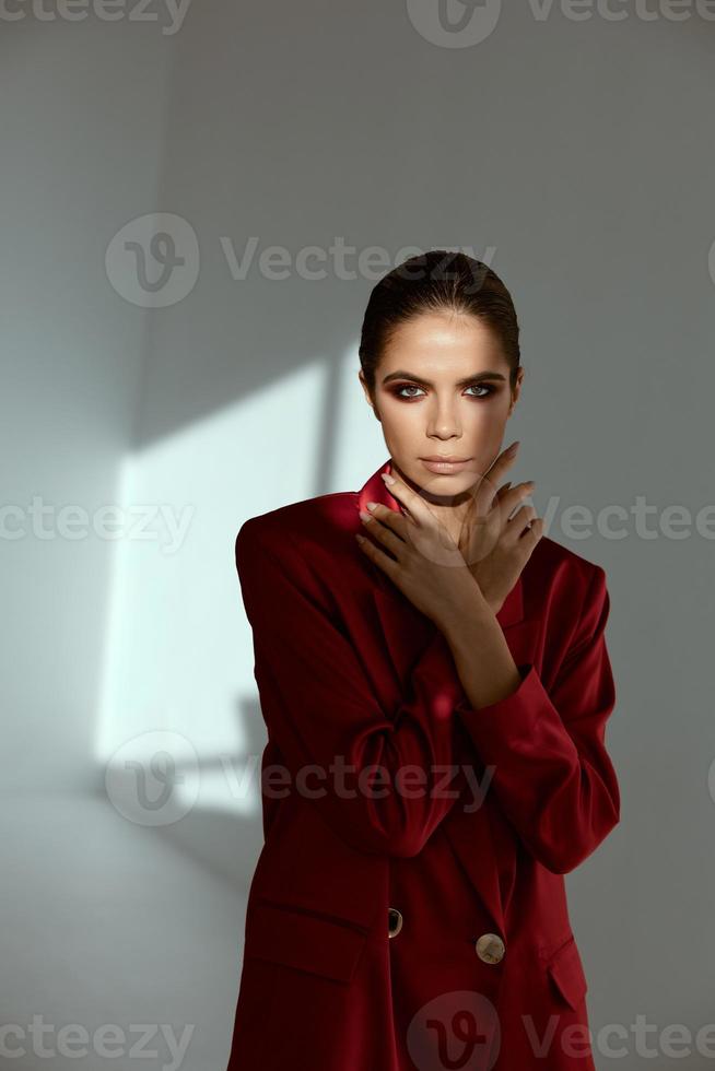 brunette in red jacket holds hands near face charm makeup photo