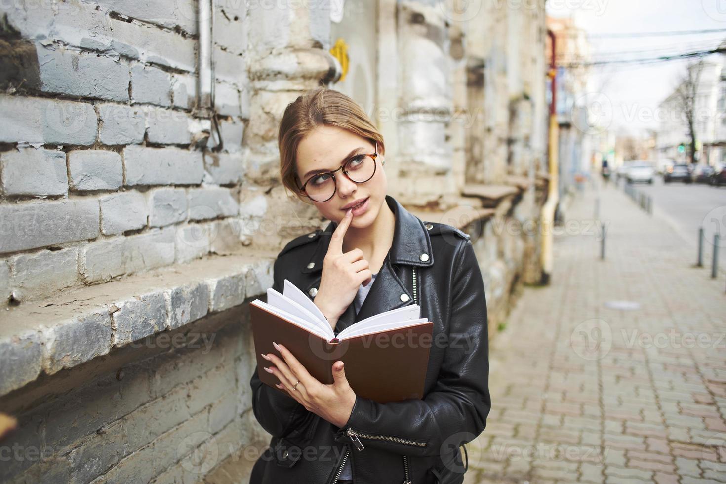 A woman with a notepad walks down the street near a building in the city photo