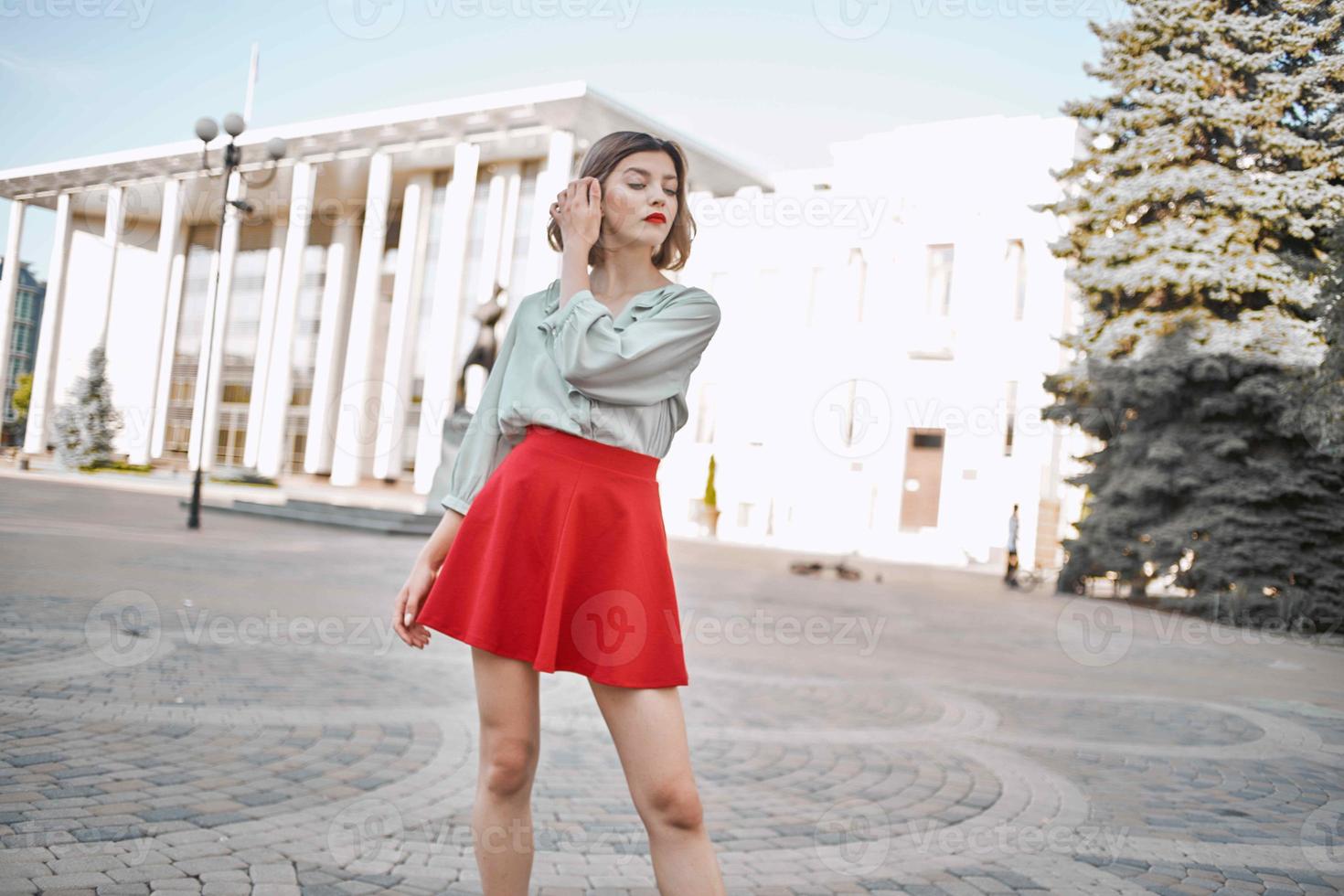 bonito mujer en rojo falda caminando en el ciudad al aire libre foto