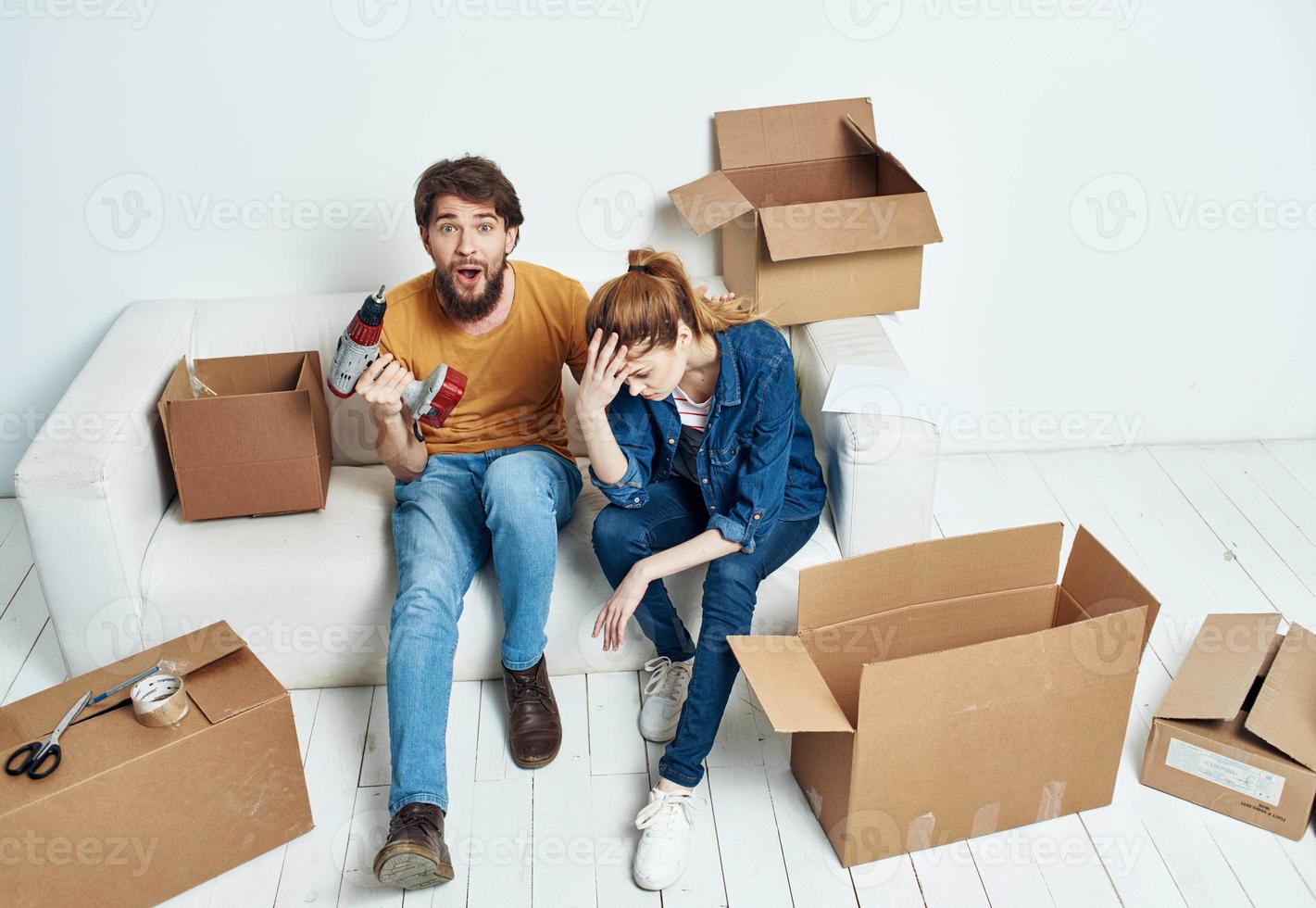 cheerful man and woman on the couch moving interior cardboard boxes photo