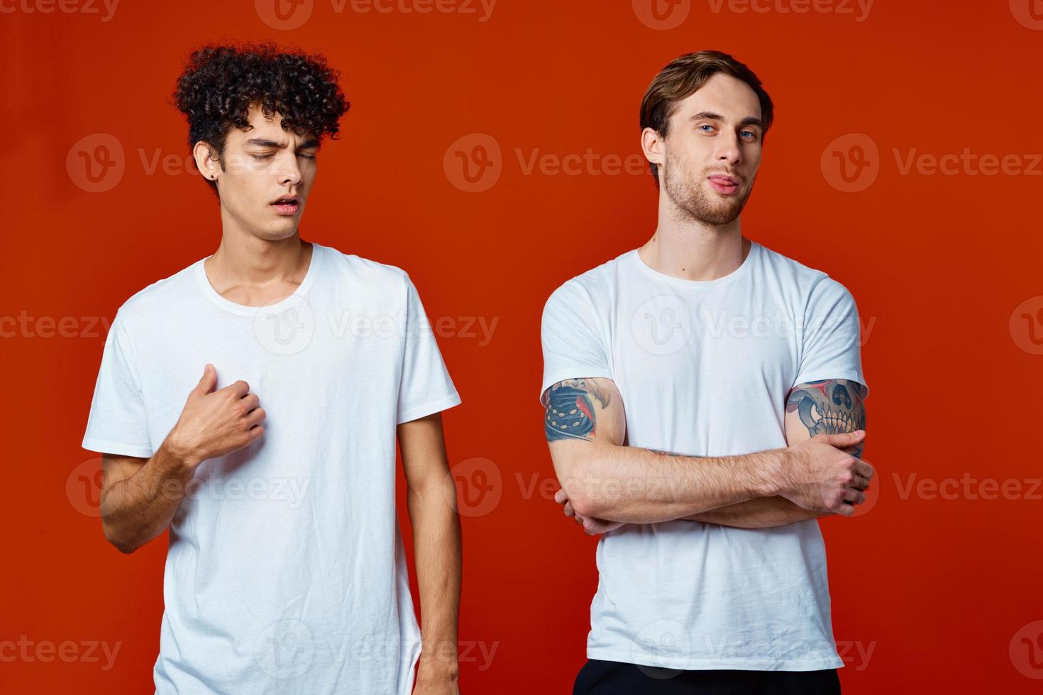 Two men in white t-shirts stand next to communication red background photo