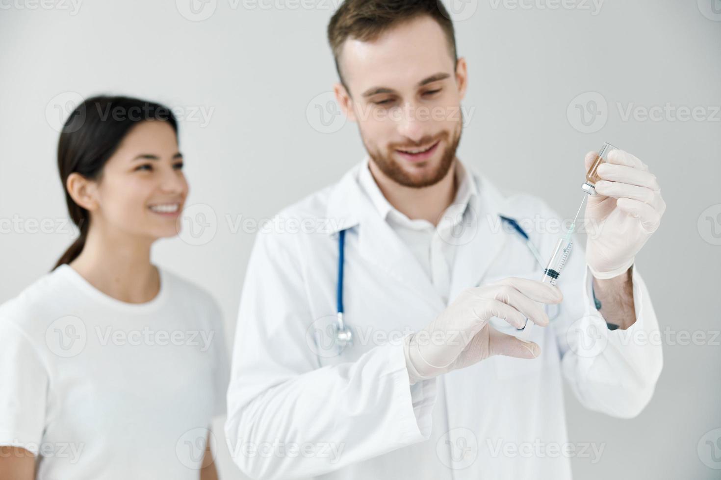 happy female patient looking at syringe with covid-19 vaccine in doctor's hands photo