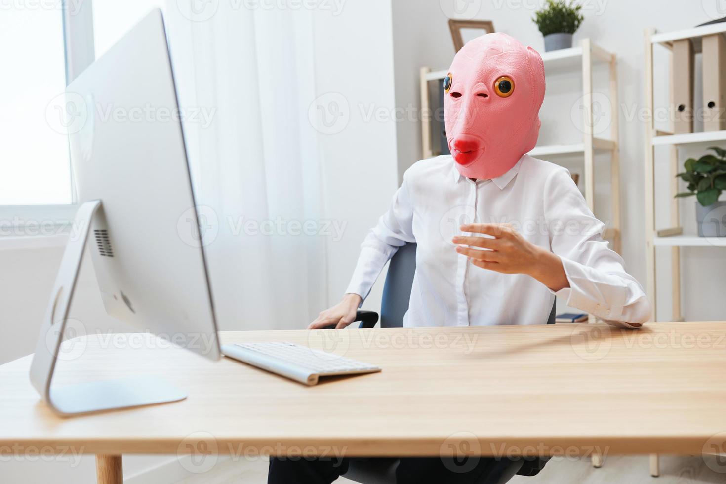 Focused funny crazy businesswoman worker freelancer in pink fish mask work on computer online pondering or making decision thinking of problem solution in light modern office. Copy space photo