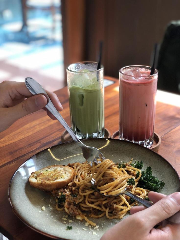 spaghetti bolognese hand in frame with drink photo