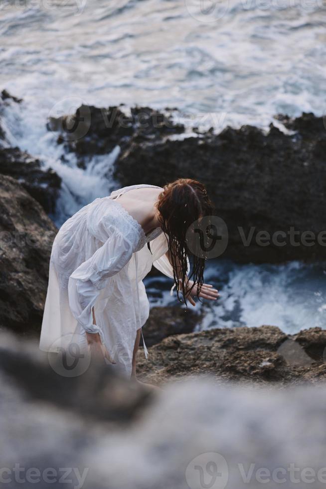 pretty woman in white dress stands on the rocks landscape ocean unaltered photo