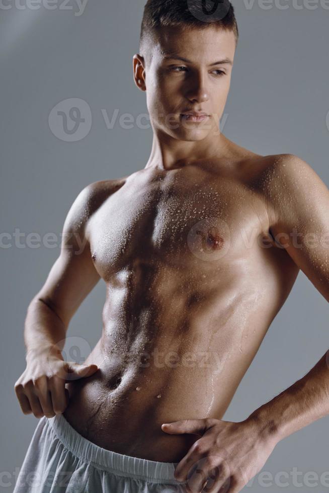 athlete with naked torso holds hands on belt on gray background cropped view photo