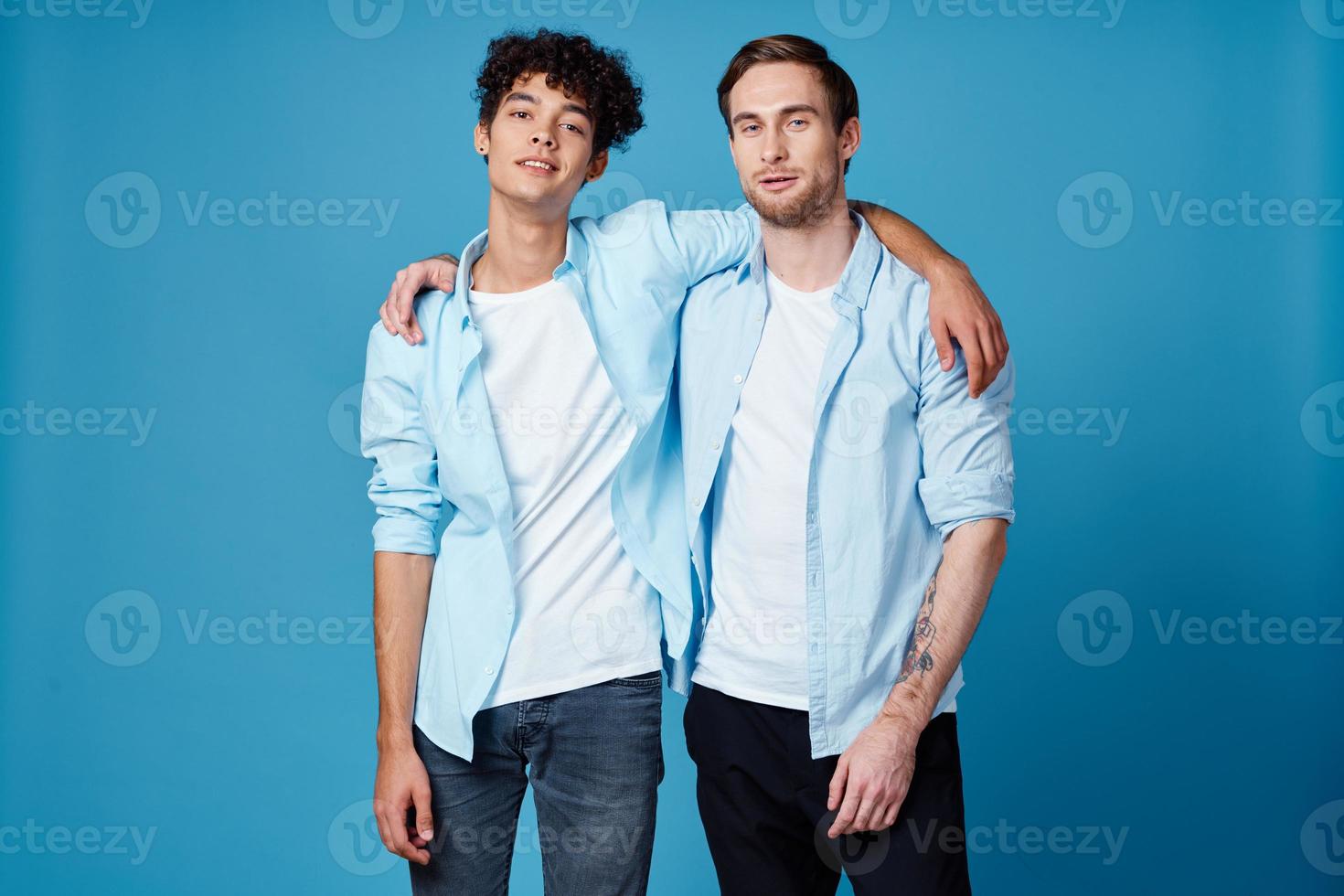 guy with curly hair in a shirt and a t-shirt on a blue background and a young man friends fun photo